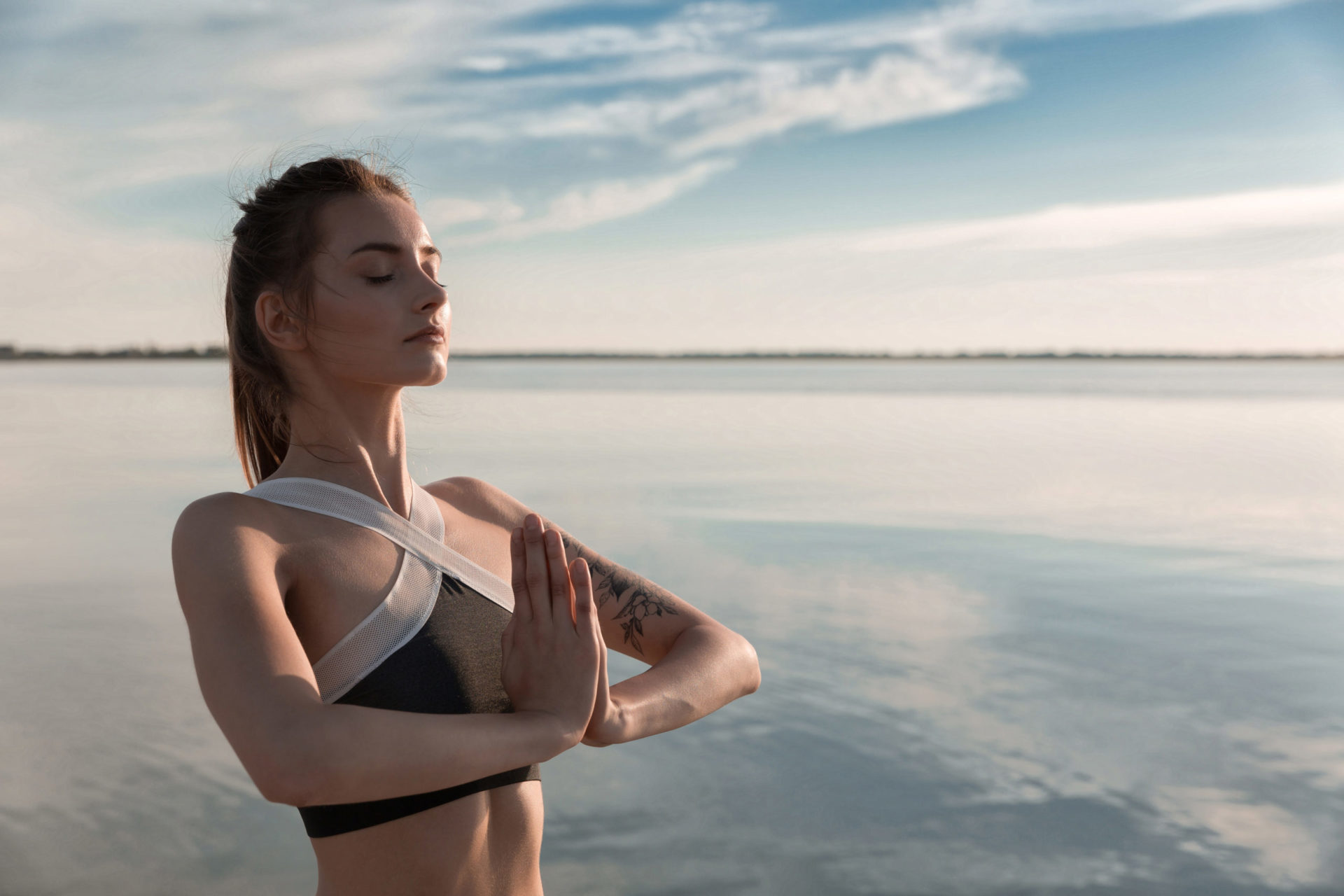 Sports beautiful woman at the beach meditation.