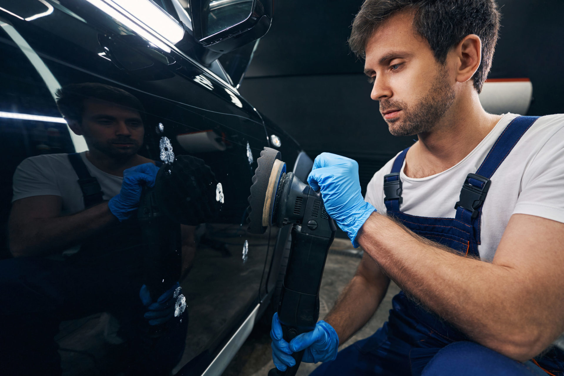 Caucasian repairman polishing body of car in automotive service